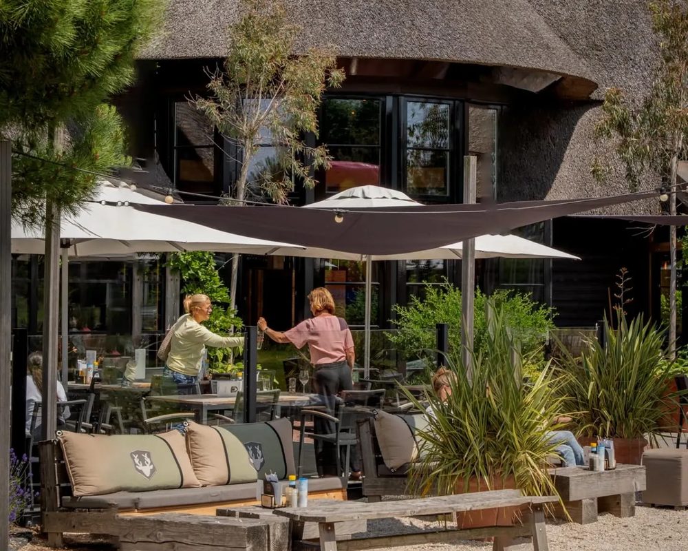 Het terras van Venneper Lodge met loungebanken en parasols